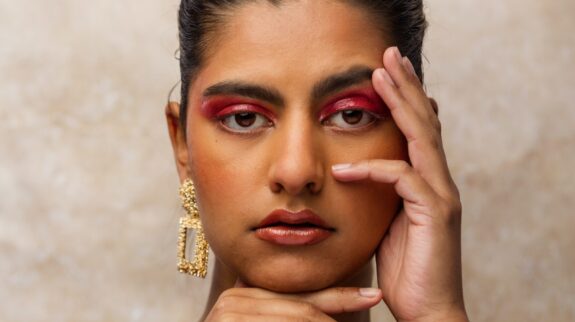 a woman looks at the camera with her hands on her face to cover scars she wants removes as part of corrective facial surgery {{brizy_dc_image_alt imageSrc=