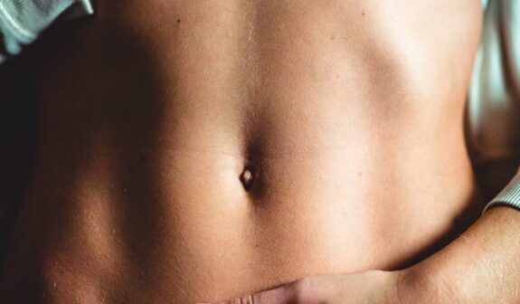 Close up photo of a woman's bare, flat abdomen after a tummy tuck (abdominoplasty) body procedure