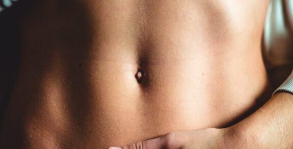 Close up image of a woman's bare, flat abdomen after a tummy tuck (abdominoplasty)