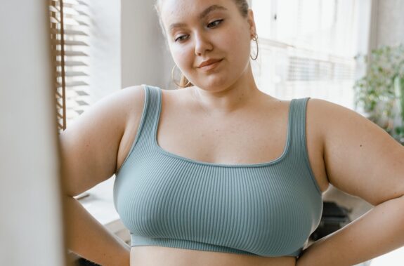 A busty woman looks in the mirror and contemplates breast reduction surgery (reduction mammaplasty)