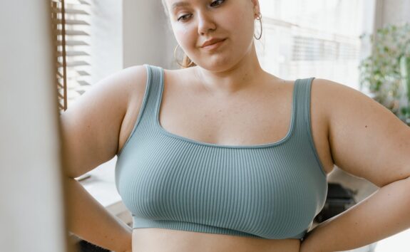 A busty woman looks in the mirror and contemplates breast reduction surgery (reduction mammaplasty)