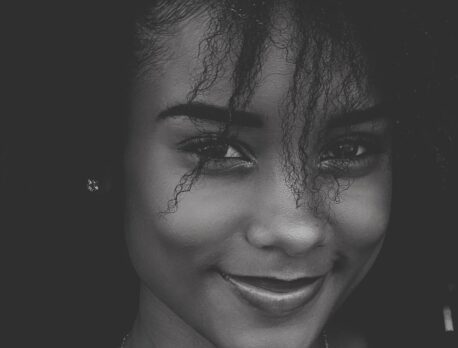 Black and white, close up of young woman's smiling face showing potential results from injectables
